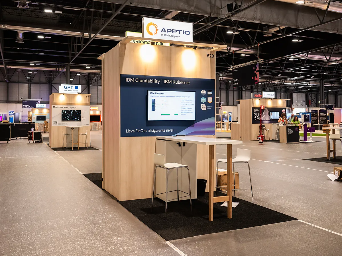 Stand van Apptio met een donkerblauwe printwand over IBM Cloudability, een scherm en een statafel met krukken