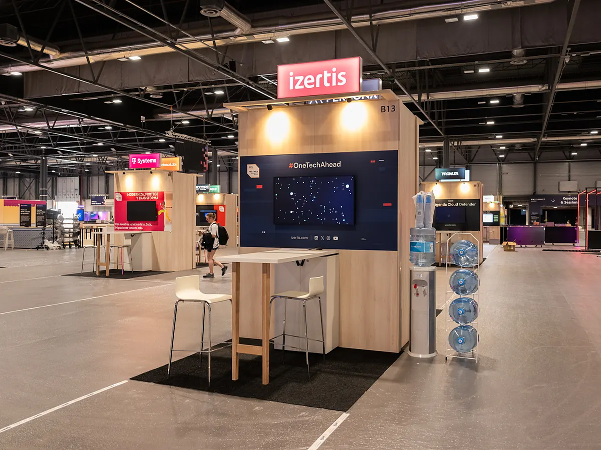 Stand van Izertis met een donkerblauwe printwand, een scherm, een statafel en een waterdispenser