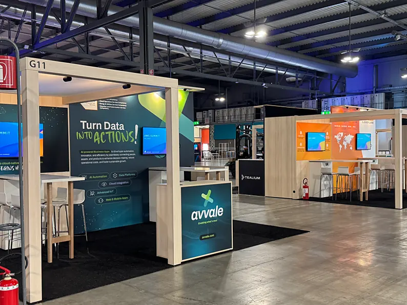 Stand van Avvale met een open portaal, een groene printwand met scherm en een balie met logo